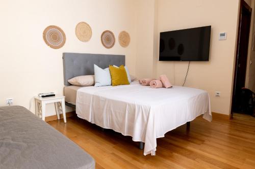 a bedroom with a large white bed and a flat screen tv at Estudio Céntrico Agua Gibralfaro con Piscina in Málaga