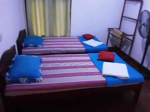 two beds in a room with blue and red pillows at LLT budget room WILPATTU in Nochchiyagama