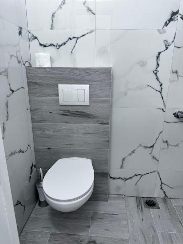 a bathroom with a white toilet and marble walls at Sevilia Rooms in Qeparo