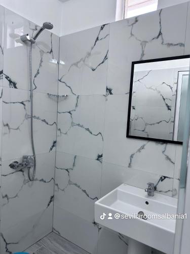 a bathroom with a shower and a sink and a mirror at Sevilia Rooms in Qeparo