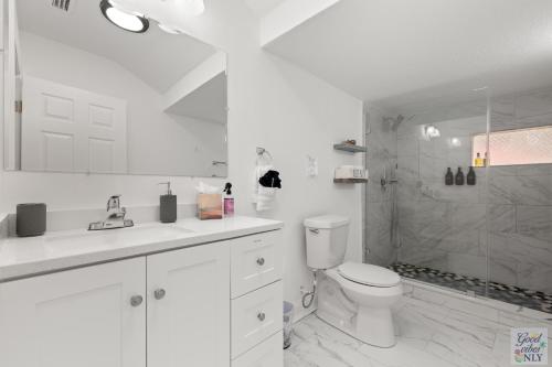 a white bathroom with a toilet and a shower at The Good Vibes Only Cottage in Tampa