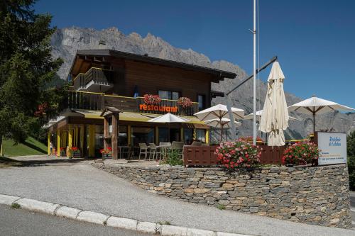 um restaurante com guarda-sóis em frente a um edifício em Hôtel Restaurant de l'Ardève & Chalet Kalbermatten em Chamoson