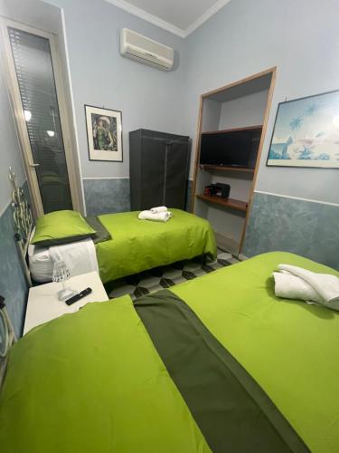 two beds in a room with green sheets at Bell'e Buono vicino aeroporto di Capodichino in Naples