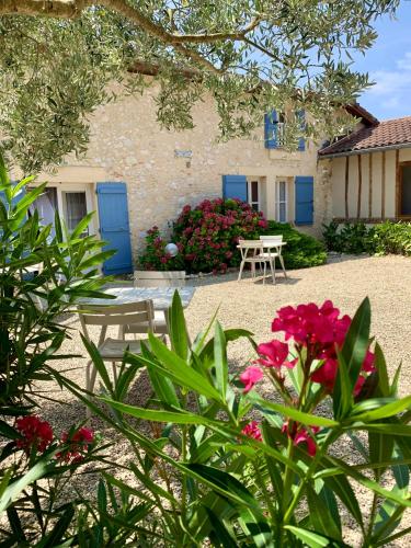 a house with blue doors and a table and flowers at Le Poutic gîte et maison d'hôtes in Créon-dʼArmagnac