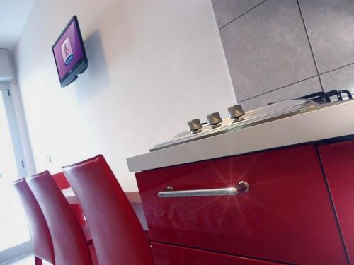 una stanza con sedie rosse e bancone con lavandino di Residence Regent Beach a Bibione