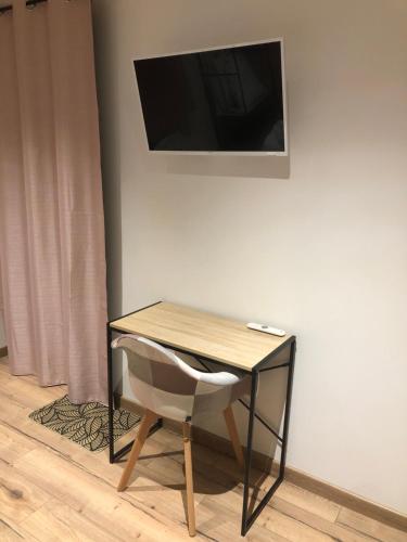 escritorio con silla y TV en la pared en Chambre privative avec spa en Louplande