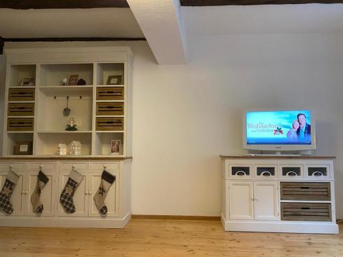 een woonkamer met een televisie op een witte kast bij FachwerkLiebe in Quedlinburg