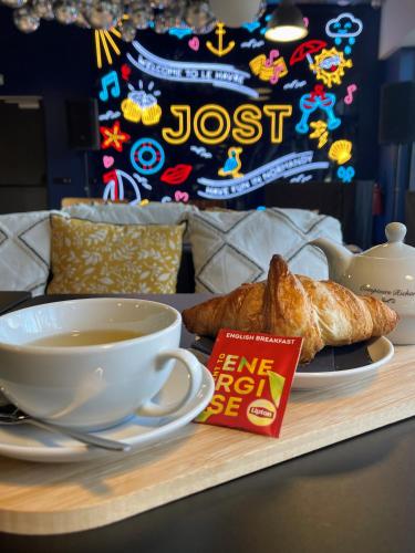 JOST Auberge de Jeunesse Le Havre Centre Gare في لو هافر: كوب من الشاي وكرواسون على صينية خشبية