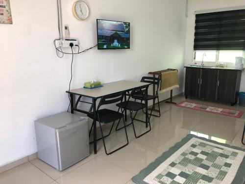 Cette chambre dispose d'une table, de chaises et d'une télévision murale. dans l'établissement MKB Homestay, à Shah Alam