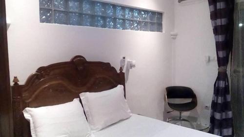 a bedroom with a bed with a wooden headboard and a chair at Villa takamelouer immo in Brazzaville
