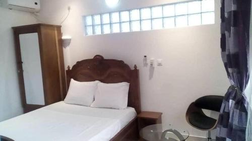 a bedroom with a bed with a wooden headboard and a window at Villa takamelouer immo in Brazzaville