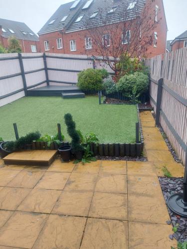 a backyard with a lawn with plants and a fence at Royal house in Ilkeston