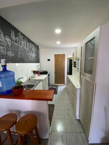 a kitchen with a counter with two chairs and a sink at Casa descanso lluta in Arica