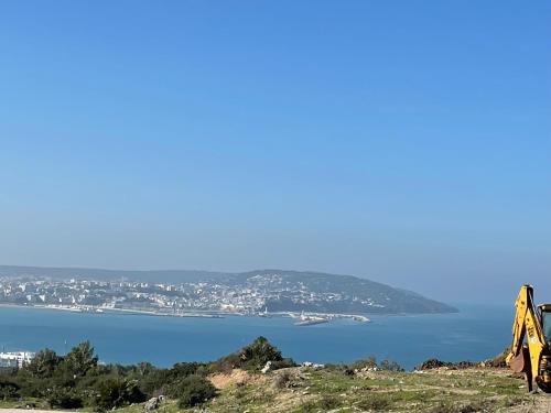 a yellow bulldozer on a hill next to a body of water at Tangier Mediterranean Villa in Tangier