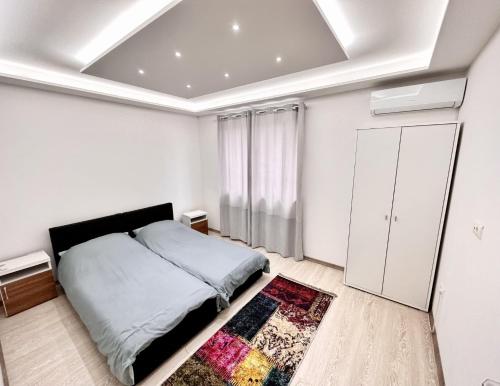 a white bedroom with a bed and a rug at Villa Max in Sarajevo