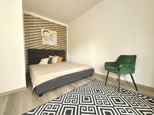 a bedroom with a bed and a green chair at Apartment 1 in the Bank House in Kutná Hora
