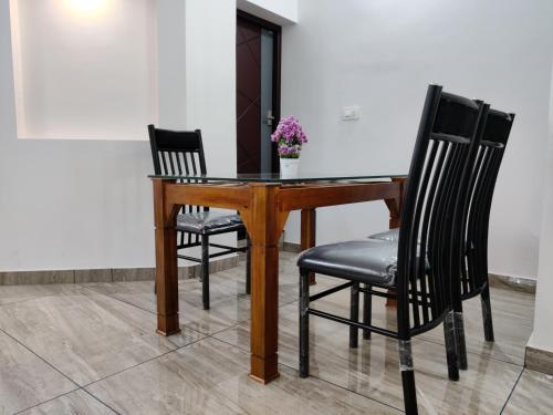 a wooden table with two chairs and a vase with flowers at Abode Homestay Alleppey Near Omanapuzha Beach in Alleppey