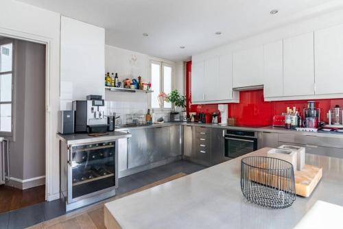 une grande cuisine avec des placards rouges et blancs dans l'établissement Amazing Flat Sénat, à Paris
