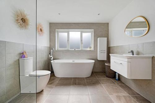 a bathroom with a tub and a toilet and a sink at 3BD Retreat Boothstown Manchester in Ellenbrook