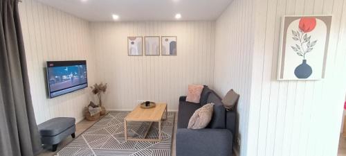 ein Wohnzimmer mit einem blauen Sofa und einem Tisch in der Unterkunft Svencelė Cottage K18 in Svenele