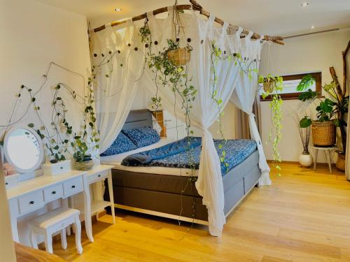 ein Schlafzimmer mit einem Himmelbett mit Vorhängen und einem Schreibtisch in der Unterkunft House of the Rising Sun in Hauzenberg