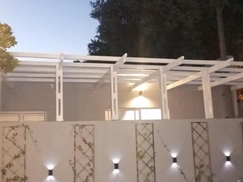 a white pergola on a white house with lights at Dalau on Main in Paarl