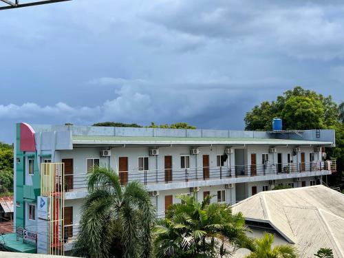 a white building with a blue roof and palm trees at Japandi-inspired Hideaway in Dumaguete