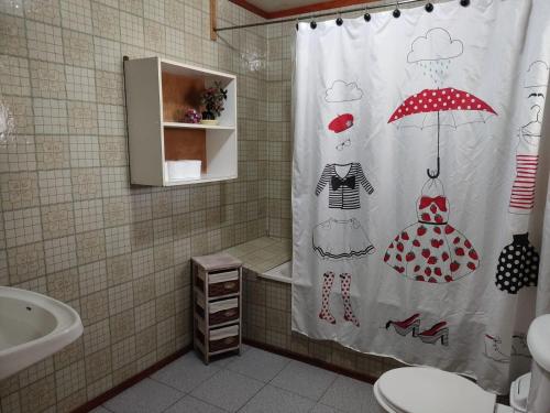 a bathroom with a shower curtain with a woman with an umbrella at Hospedaje Martita. in Putemún