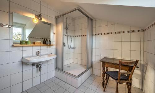 a bathroom with a shower and a sink and a chair at Hotel Schmiedhubers in Engelsberg