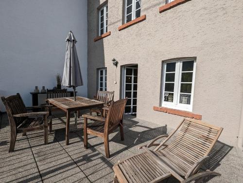 a patio with a table and an umbrella and chairs at Ferienhaus MaLu Zell in Zell an der Mosel