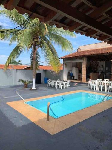 a swimming pool with tables and chairs and a palm tree at Chácara Martins in Olímpia