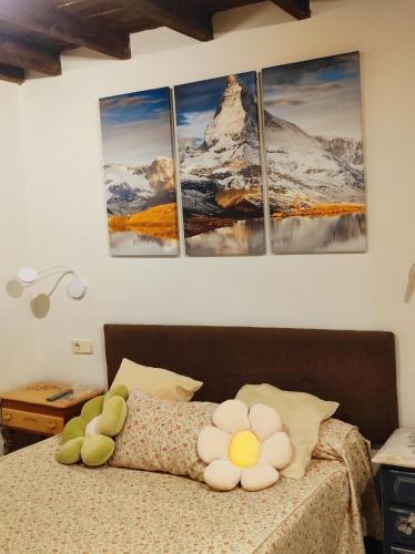 a bedroom with a bed with four paintings on the wall at Casita Roja sin cocina in Cercedilla