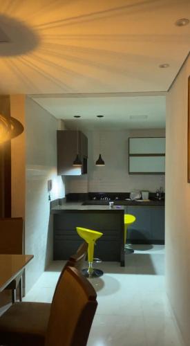 een keuken met een tafel en gele stoelen. bij Apartamento em área nobre in Conselheiro Lafaiete
