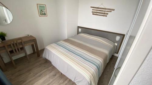 a small bedroom with a bed and a table at Appart à St Martin de Ré in Saint-Martin-de-Ré