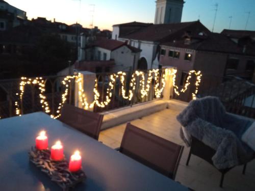 zwei Kerzen auf einem Tisch auf einem Balkon mit Lichtern in der Unterkunft VENICE HOLIDAY TERRACE in Venedig