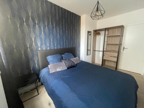 - une chambre avec un lit bleu et un mur dans l'établissement Style Loft Chic : T2 avec Chambre Parentale -Top Séjour Arras, à Arras
