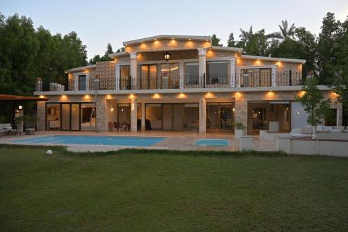 une grande maison avec une piscine en face de celle-ci dans l'établissement منتجع بيت الريف, à Al Hofuf