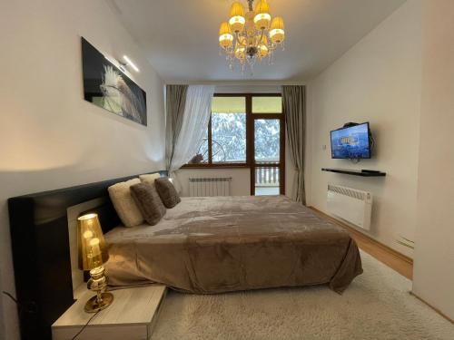 a bedroom with a large bed and a chandelier at Luxury Apartament in "Sequoia" 2 in Borovets