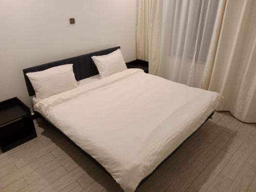 Bett mit weißer Bettwäsche und Kissen in einem Zimmer in der Unterkunft Two bedroom Apartment at Yaya in Nairobi