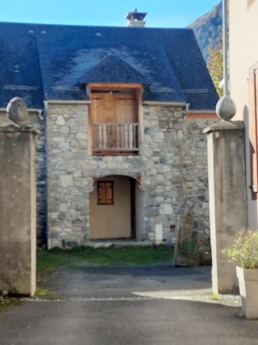 Appartement cœur vallée d'Aure في Vielle-Aure: منزل حجري قديم مع شرفة وباب