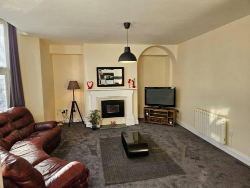 a living room with a couch and a television at Carlisle City Centre. Spacious Apartment. Ideal location. in Carlisle