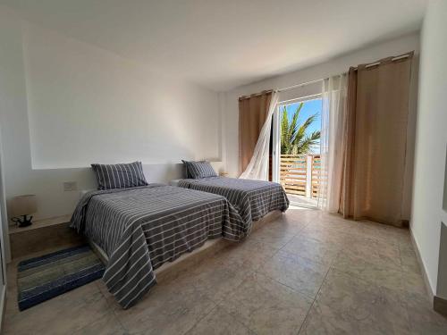 1 dormitorio con 2 camas y ventana grande en Yellow Heron House, en Puerto Villamil