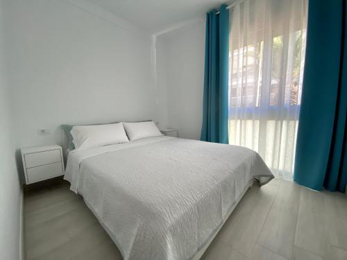 a white bedroom with a bed and a window at Casa Antonio - apartamento Luna in Playa de San Juan