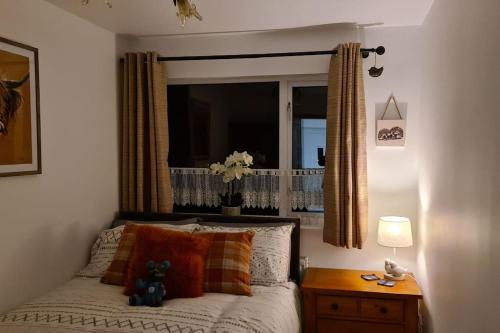 a bedroom with a bed with a window and a table at Northlea-Scottish style cottage in Inverness