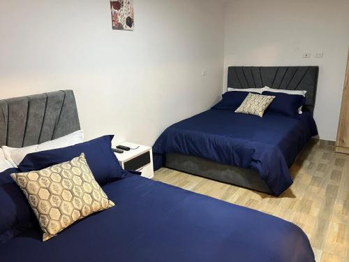 two beds in a room with blue sheets and pillows at APARTASUITES BOGOTA 53 - 101a in Bogotá