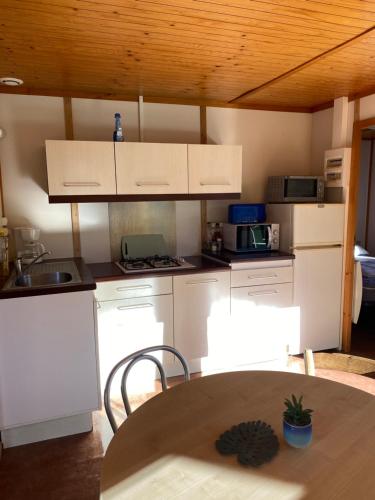 a kitchen with white cabinets and a wooden ceiling at Charmant logement à la campagne, au calme in Manhac