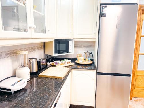 a kitchen with white cabinets and a stainless steel refrigerator at Casa junto al Mar in El Ejido