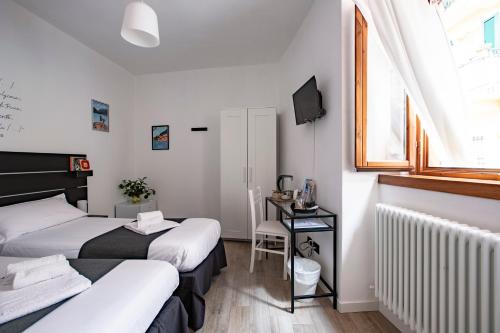 2 łóżka w pokoju z biurkiem i oknem w obiekcie La Casa del Sarto - Rooms and Apartments w mieście Lecco