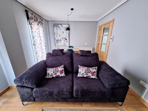 a purple couch with pillows in a living room at Apartamento Turístico El Canalizo I in Candelario