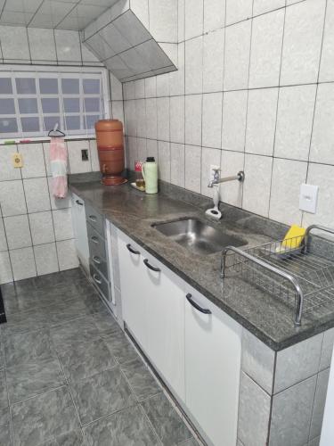 a kitchen with a sink and a counter top at Casa com dois quartos,dois banheiros,sendo uma suíte,sala de estar cozinha e garagem in Poços de Caldas